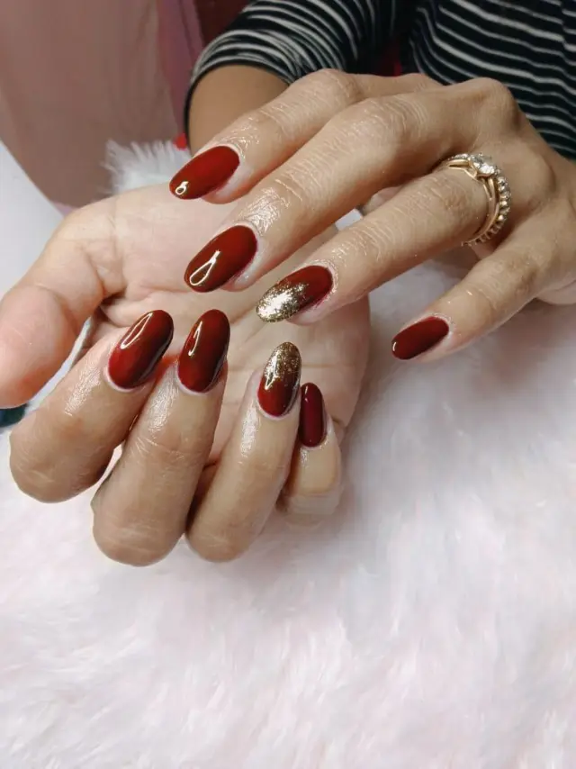 Deep red glossy gel manicure with gold accent nail